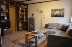 Wohnzimmer mit neuem Pelletofen und gut bestückter Bibliothek. Hier können Sie sich an Schlechtwettertagen mit Büchern, Hörbüchern oder Spielen die Zeit vertreiben. - Bild 6: Eifel-Ferienhaus Fliegenpilz - für Ihren Urlaub mit und ohne Hund