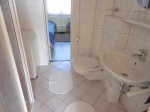 Badezimmer Das weiß geflieste Badezimmer mit geräumiger Duschkabine. Auch eine Waschmaschine für den kleinen Waschtag zwischendurch steht bereit. Eine Verbindungstür zum Schlafraum nach Osten öffnet den Blick auf die Ostsee. - Bild 16: Großzügige Ferienwohnung mit Meerblick und Infrarotsauna in Hohwacht