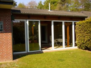 Die bodentiefen Fenster des Wintergartens lassen sich komplett zur Seite schieben; so entsteht ein luftiger regengeschützter Freisitz. - Bild 3: Ferienhaus "Kristina" an der ostfriesischen Nordseeküste - Hunde erlaubt