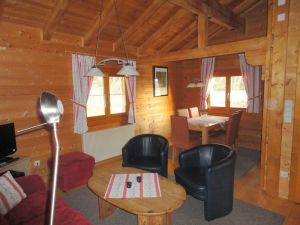 Für die Mahlzeiten stehen im Eßbereich ein großer Tisch und 5 Stühle bereit.
Im oberen Teil ist die offene Holzkonstruktion des Daches zu sehen. - Bild 2: Blockhausurlaub Bayerischer Wald - ideal für Familien mit Kindern und Hund