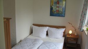 Hier sehen Sie das kleine Schlafzimmer mit dem 140er Bett, welches auch mit einem TV ausgestattet ist. Das Haus hat insgesamt 3 Schlafzimmer. 2 x mit 180er Doppelbetten im Souterrain und 1 x in der Paterre mit einem 140er Bett. Es ist also Platz für maximal 6 Personen. Bedenken Sie dann aber, dass nur 1 Duschbad zur Verfügung steht. - Bild 9: Nahe Grömitz Neustadt Pelzerhaken Rettin Ostsee Hunde willkommen
