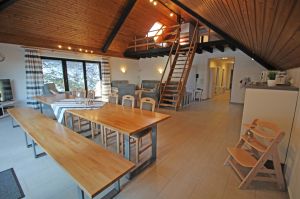 mit Esstisch, Küche und gemütlicher Ecke. Auf diesem Bild sieht man auch die Raumspartreppe zur Empore. - Bild 1: Ferienwohnung EifelNatur 6 - Große + komfortable FeWo für 12 Pers.
