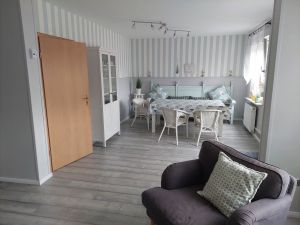 Gemütliches Esszimmer mit Rattankorbsesseln und einer alten Kirchenbank. Ein Kinderhochstuhl ist auch vorhanden. Desweiteren befindet sich in diesem Bereich ein XL-Hundekörbchen aus Kunstleder. - Bild 8: Nordseenahes Ferienhaus in Ostfriesland für Familie und Co