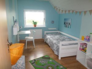 Hier befindet sich ein Ausziehbett, so dass auch hier zwei Kinder schlafen können. Ein Kleiderschrank, ein Klapptisch mit Stuhl und ein Regal sind vorhanden. Desweiteren findet man auch hier Spielsachen, Malsachen usw. für die Kinder. - Bild 17: Nordseenahes Ferienhaus in Ostfriesland für Familie und Co