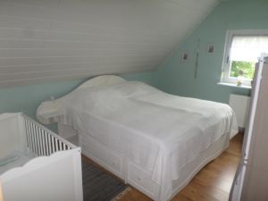 Hier finden sie ein Doppelbett, ein Gitterbett für Kleinkinder sowie ein Kleiderregal. Die grossen Schubfächer unter den Betten können als Stauraum genutzt werden. - Bild 18: Nordseenahes Ferienhaus in Ostfriesland für Familie und Co
