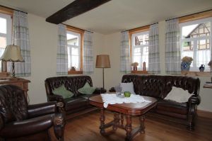 Im großen Wohnzimmer steht eine Ledergarnitur, bestehend aus 3-Sitzer, 2-Sitzer und Sessel. Der Bodenbelag ist Eichenholz. Ein Kachelofen spendet an kühlen Tagen wohlige Wärme. - Bild 13: Ferienhaus Kieselbach am Rande der Thüringschen Rhön