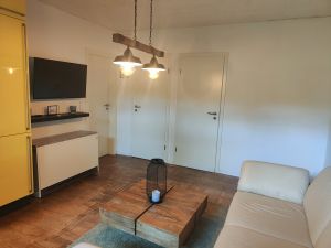 Das Wohnzimmer ist mit einem Fernseher und einem Nachtspeicherofen ausgestattet. Hier findet auch ihr vierbeinige Freund einen Platz. - Bild 10: Haus mit Zaun an beliebten Wanderrouten mit Blick in den Sternenhimmel