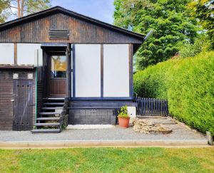 Vom Garten aus können Sie durch das Schlafzimmer 1 ins Ferienhaus gelangen oder Sie gehen um das Ferienhaus an der Hecke vorbei und kommen so zum Haupteingang. - Bild 25: Haus mit Zaun an beliebten Wanderrouten mit Blick in den Sternenhimmel