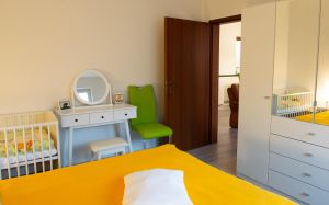 Blick aus dem Schlafzimmer ins Wohnzimmer, großer Kleiderschrank und optionales Babybett - Bild 11: Ferienwohnung "Die Käuzchenkuhle" - Alleinlage im Wald