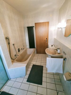 Das Tageslicht Bad ist gut ausgestattet mit WC - Waschbecken - Spiegel, sowie Vorratsschränken in denen ein kleines Kontingent an Klopapier und auch ein kleiner Fön vorhanden sind.
Neben der Dusche gibt es noch eine Wanne zum entspannen. Dieser Raum verfügt über eine Fussbodenheizung. - Bild 5: Ferienwohnung Vietheer im Holsteiner Auenland